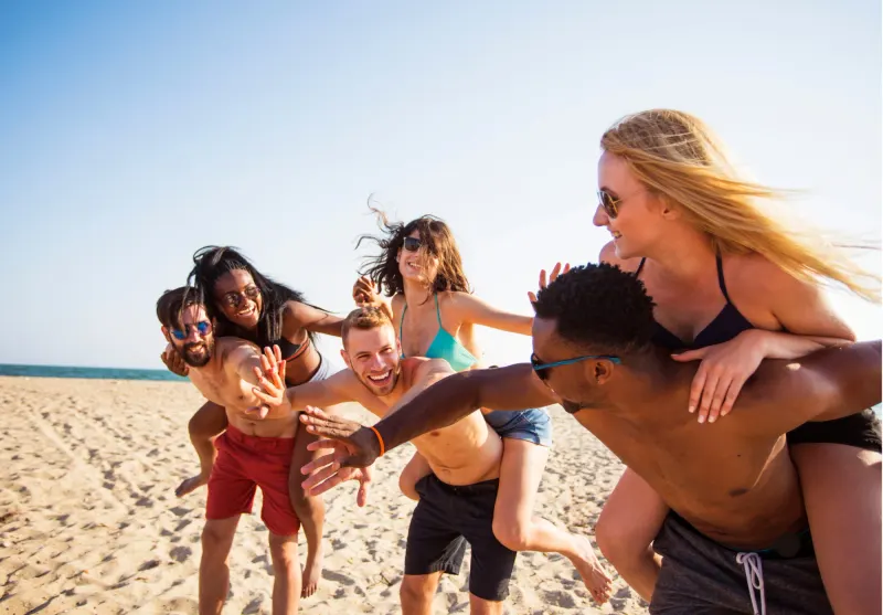 Grupo de amigos jugando y riendo en la playa