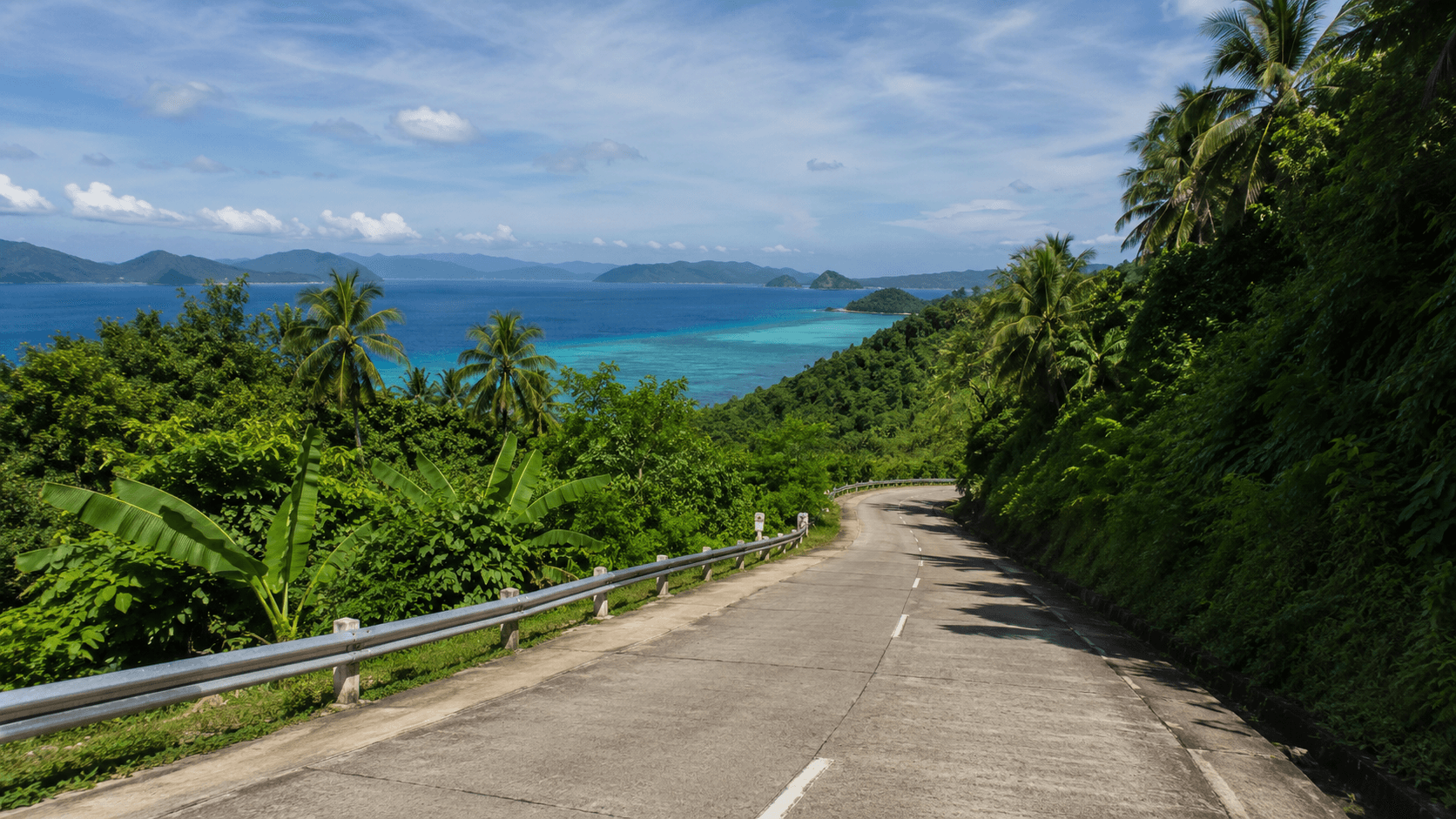 Carretera costera de Palawan con vegetación tropical y mar turquesa al fondo, Filipinas